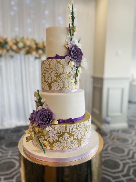 Simrat, 4 tier gold and purple theme wedding cake with stencilled damask detail and sugar flowers Purple And Cream Wedding Theme, Gold And Purple Wedding Cake, Lavender Gold And White Wedding, Lilac And Gold Wedding Theme, Lavender And Gold Wedding Theme, Gold And Purple Wedding Theme, Purple Gold And White Wedding, Gold And Lavender Wedding, Lilac And Gold Wedding