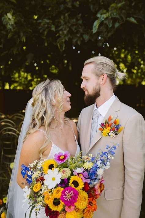 ​This vibrant and funky wildflower wedding at Ojai Rancho Inn was ​eclectic, bold,​ whimsical, artistic, and fun! Our musician bride had a colorful statement ​bridal ​bouquet with ​a rainbow of ​summer wildflowers and sunflowers​. ​Our groom wore a ​colorful ​floral pocket​ boutonniere​!​ Dried ​wildflowers ​hung ​from trees, 400 sunflower heads floated in the pool, and guest dined al fresco under string lights. ​​Photographer: The Shalom Imaginative . Pocket Boutonniere Wildflower, Wildflower Wedding Suit, Whimsical Wedding Groom, Wild Flower Wedding Groomsmen, Spring Wedding Bouquets Wildflowers, Sunflower And Wildflower Wedding, Summer Wildflower Bouquet Wedding, Multicolor Wedding Bouquet, Fall Rainbow Wedding