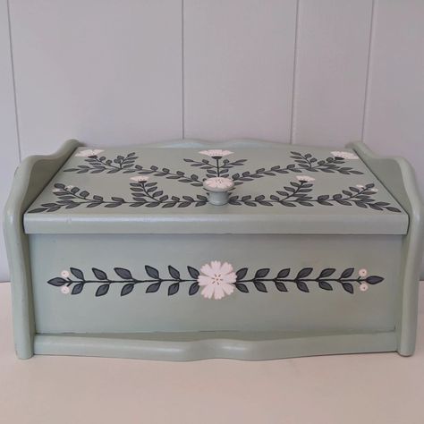 Pine bread box hand painted with a pretty blue/green and lots of bright white flowers with little gold details. #breadbox #handpainted #colorfulhome #colorfulkitchen #kitchendesign #kitchendecor #floraldesign #folkart #pastel #pastelhome #pastelhomedecor #pastelkitchen #floraldecor Pine Bread, Bread Box Painting Ideas, Vintage Metal Bread Box Makeover, Hand Painted Wooden Box Ideas Flowers, Ceramic Bread Box, Vintage Bread Boxes Metal, Pastel Kitchen, Pastel Home Decor, Bread Boxes