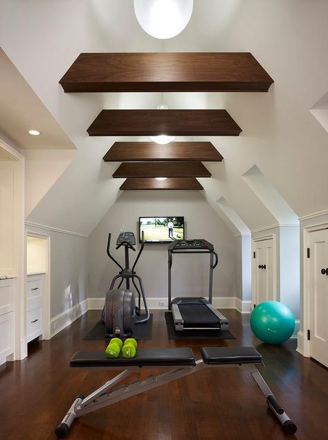 Attic home gym boasts a vaulted cieling adorned with wood beams placed over gym equipment facing a flat panel tv. Home Gym Closet, Gym Closet, Attic Library, Attic Renovation Ideas, Yoga Ashtanga, Finished Attic, Media Room Design, Attic Playroom, Attic Loft