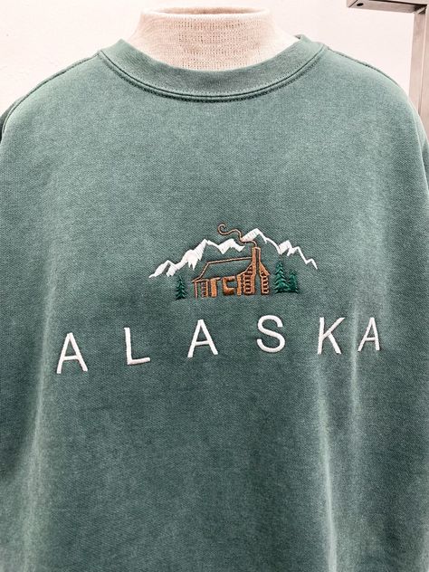 Our Tomorrow brand featuring an embroidered cabin in the mountains. Our Alaska sweatshirt is the perfect cozy sweatshirt. Comfort Colors sweatshirt 80% cotton, 20% polyester Premium heavy fabric Vintage Alaska Sweatshirt, Cozy Oversized Sweatshirt For Outdoor, Cozy Crew Neck Sweatshirt For Outdoor, Outdoor Crew Neck Cotton Sweater, Outdoor Cotton Sweater With Letter Print, Cotton Crew Sweater For Outdoor, Cotton Crew Neck Sweater For Outdoor, Outdoor Cotton Crew Sweater, Winter Crew Sweatshirt With Letter Embroidery