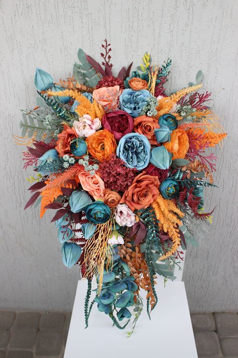 All the flowers and greenery is artificial and of high quality! Rustic Wedding Bride Bouquet, Teal And Orange Flower Arrangements, Teal Burgundy Orange Wedding, Unique Fall Wedding Centerpieces, Flowers For October Wedding, Dark Teal And Burgundy Wedding Flowers, Wedding Flowers Blue And Orange, Aztec Wedding Theme, Fall Wedding Bright Colors