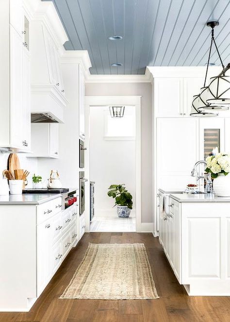 A Grosvenor Linear Triple Pendant hangs from a blue plank ceiling over a white kitchen island boasting a farmhouse sink and a polished nickel gooseneck faucet mounted to a gray countertop. Shiplap Ceiling, Plank Ceiling, Blue Ceilings, Grey Countertops, White Kitchen Island, Colored Ceiling, Kitchen Ceiling, Farmhouse Dining Room, Painted Ceiling