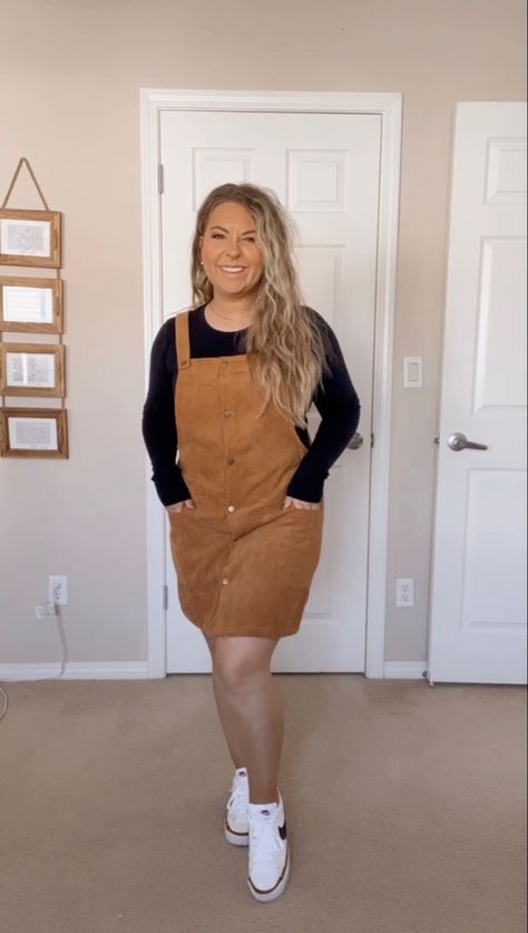 Black long sleeve shirt under a brown corduroy dress. White Nike sneakers. Overalls Dress Outfit Fall, How To Style Overall Dress, Overall Dress With Sweater, Courdory Overalls Outfits, Corduroy Dress Outfit Fall, Cute Fall Overall Dresses, Courdory Dress Outfit, Corduroy Jumper Outfit, Corduroy Dress Outfit Winter