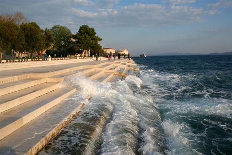 The Sea Organ is an experimental musical instrument that is located in Zadar, Croatia. Beneath the white marble steps, a series of tubes create a system that could be described as a large piano. When the waves or the wind flow through the holes, they interact with the organ to create random harmonic sounds. Sea Organ, Zadar Croatia, Unbelievable Facts, Tourist Information, Crashing Waves, Zadar, Heroes Of Olympus, Zagreb, Dubrovnik