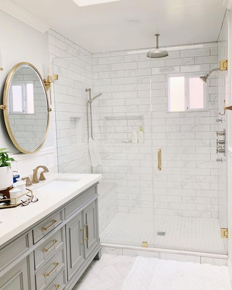 The designer of this small bathroom was committed to the color scheme of gray and gold. The spacious shower with brushed nickel faucets is finished with gold hardware on the transparent glass door. Where the vanity stands, circular gold mirrors are situated in between gold sconces, over an elegant gray vanity with white vanity tops. Gold Sconces, Luxurious Bathtubs, Bathroom Cabinets Diy, Gold Mirrors, Bathroom Freestanding, Gray And White Bathroom, Frameless Glass Doors, Brushed Nickel Faucet, Gray Vanity