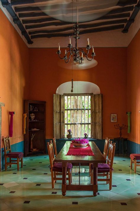 The main hacienda dining room is furnished with traditional Mexican furniture. The lower half of the room is painted a deep blue as a contrast to the orange walls.  [i][link url="https://www.rizzolibookstore.com/casa-mexico-home-merida-and-yucatan"]Casa Mexico: At Home in Merida and the Yucatan[/link] by Annie Kelly and photographed by Tim Street-Porter ([link url="http://www.rizzoliusa.com/"]Rizzoli[/link], £45).[/i] Mexican Style Dining Room, Mexican Style Interior, Mexican Dining Room, Mexico Interior Design, Mexican Home Interior, Vacation House Decor, Mexican Villa, Mexican Interior Design, Theme Restaurant