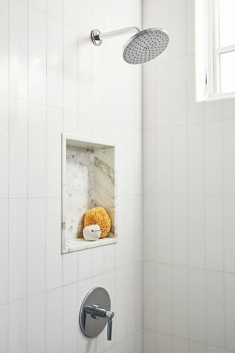 Walk-in shower is clad in white vertical wall tiles and fitted with a chrome round rain shower head fixed over a mosaic marble tiled niche. Tiled Niche, Chrome Shower Fixtures, White Plank Walls, Shower Accent Tile, Tile Walk In Shower, White Tile Shower, Tile Backsplash Bathroom, Mosaic Marble, Subway Tiles Bathroom