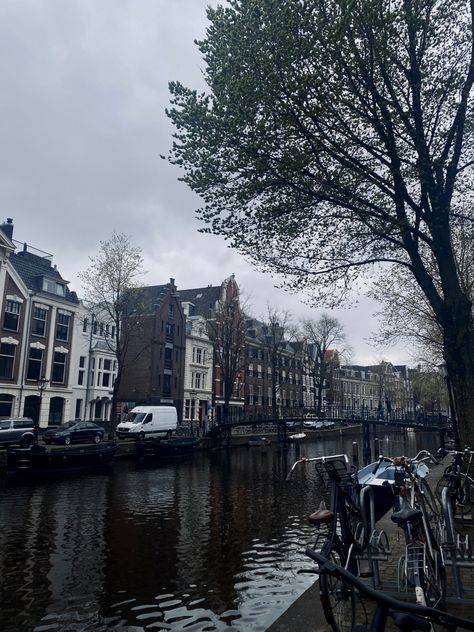 A canal view in Amsterdam, The Netherlands A canal during spring time with gloomy skies, bikes on the side and people wearing many layers of clothes to not freeze in the cold Netherlands wind Amsterdam; The Netherlnads; canal; amsterdam aesthetic; trees; bikes; bike aesthetic; houses; dark; dark aesthetic; spring; travel; amsterdam travel; cars; gloomy skies; skies Amsterdam Dark Aesthetic, Canal Amsterdam, Layers Of Clothes, Netherlands Aesthetic, Aesthetic Trees, Amsterdam Aesthetic, Travel Amsterdam, Bike Aesthetic, Spring Travel