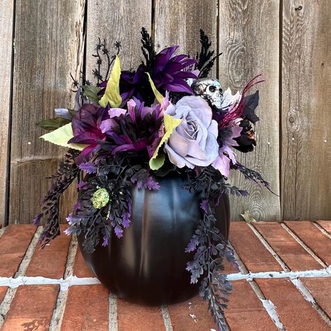 This  flower arrangement features all the things that make Halloween fun and  beautiful.  The black artificial pumpkin has the lid carved out and attached to the back of the arrangement.  The center is filled with flowers in the hues of gray, purple, black, and green.  Fun picks feature a silver skull, a purple and a green spider small spider web.  Black and purple feathery sprays and glittery berry sprays complete this arrangment   The pumpkin arrangement measures 15" in heigth and 12" at the widest part.   Item #FLR - 84 Moon Floral Arrangement, Spooky Flower Arrangements, Spooky Apartment, Flower Diy Paper, Halloween Flower Arrangements, Quince Planning, Halloween Floral Arrangements, Paper Flower Diy, Green Spider