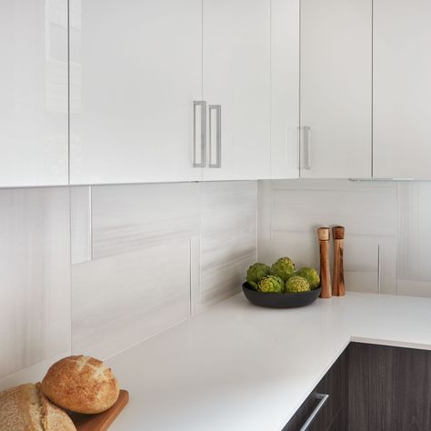 Creating a modern kitchen backsplash can feel daunting, but using a larger tile can be the perfect solution! This pattern with our Themar Bianco Lasa 12x24 porcelain tile adds a clean look to this ultra-modern space. https://www.arizonatile.com/en/products/recycled-material-content/themar Features Products: Themar Bianco Lasa and Absolute White Polished Quartz 12x24 Tile Backsplash Kitchen, 12x24 Backsplash Kitchen, White Tiles Kitchen, White Glossy Kitchen, Kitchen Budget, Porcelain Tiles Kitchen, Glossy Kitchen, Kitchen Ceiling Design, Kitchen Backsplash Trends