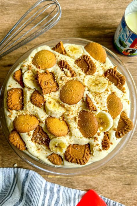 Biscoff banana pudding served in a big, clear glass bowl, topped with nilla wafers and biscoff cookies. Next to the bowl is a whisk, and a tin of condensed milk. Cookie Banana Pudding, Biscoff Pudding, Creamy Banana Pudding Recipe, Biscoff Banana, No Bake Biscoff, Banana Spring Rolls, Banana Cream Pudding, Creamy Pudding, Comfort Desserts