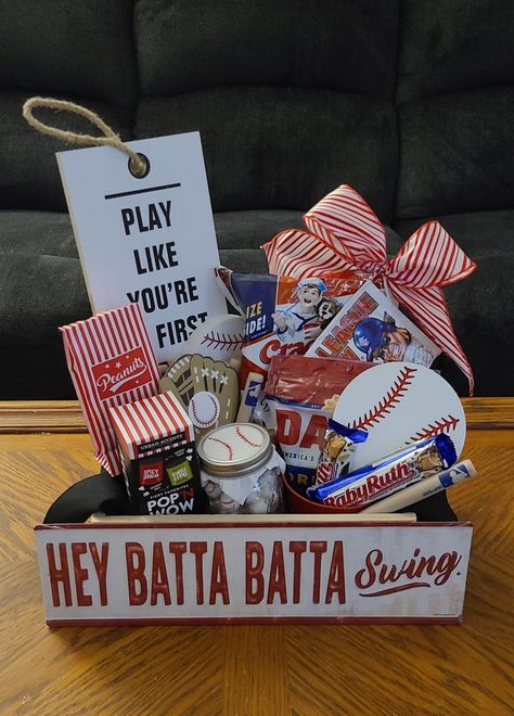 Baseball basket: Cracker Jacks, David sunflower seeds, Big League Chew, tin bucket for shells, Baby Ruth bars, MLB baseball bat pens, MLB cup(party city) table decor wooden baseball, wood sign, tin sign, Planters Peanuts inside peanut bags, Mason jar with candies, tissue paper with baseball stitching drawn on, popcorn kernels, crate & tin sign from Hobby Lobby, pre-painted wooden baseball & mitt from Hobby Lobby made into magnets. Add a bow if desired. Baseball Silent Auction Basket, Baseball Themed Baskets For Raffles, Baseball Themed Gifts, Baseball Candy Bouquet, Baseball Favors For Team, Baseball Gift Basket Ideas, Baseball Theme Gift Basket, Baseball Mom Gift Basket, Baseball Candy Bags Ideas