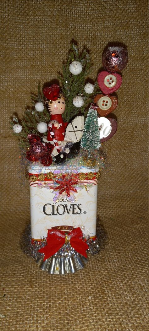 This spice tin diorama is crammed with plenty of festivity.  The tin is decorated with a bow, tinsel and gold braid. The scene on top contains a tiny wood figure on a rocking horse, wood hearts with vintage buttons, a bottle brush tree, a candy cane and bling. The spice tin rests on a tiny tart tin . It is 7 1/2 inches tall. Sucrets Tin Crafts, Cupcake Tin Christmas Craft, Tartlet Tin Ornaments, Tin Diorama, Vintage Spice Tins Christmas, Christmas Assemblage, Vintage Spice Tins, Tin Ornaments, Tin Can Art