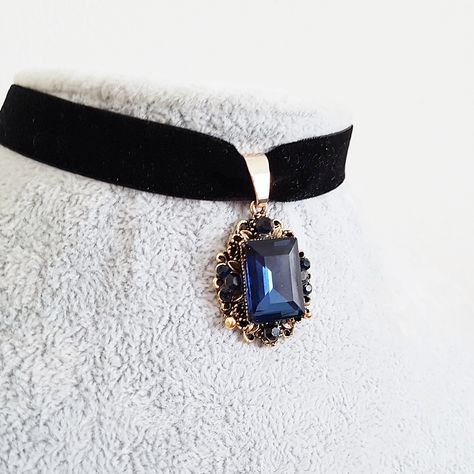 A Victorian style vintage gold plated glittering ornate dark sapphire blue crystal jewel drop is suspended from a black velvet choker. Choose your length in inches from the drop down menu.  The ornate drop measures 1 1/4 inches (30 mm) from top to bottom, and glitters with a rich blue main rectangular crystal surrounded by smaller ones. The velvet ribbon has a lobster clasp and 2 inch (50 mm) extension chain. To choose your length, measure the length of a choker that fits your neck comfortably a Princess Choker, Victorian Accessories, Blue Choker, Black Velvet Choker, Dark Sapphire, Magical Jewelry, Velvet Choker, Fancy Jewelry, Jewel Box