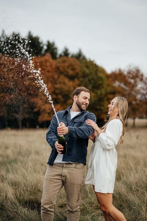 Man and woman popping champagne during their fall engagement photoshoot in Indiana. Discover more field engagement photos fall, field engagement pictures outfit ideas, and field engagement photoshoot inspiration! Book Kim for your Indiana engagement photos or Indiana wedding photography at kimkayephotography.com! Neutral Fall Engagement Photos, Engagement Photos Outfits Men Fall, Engagement Champagne Photos, Corn Field Engagement Pictures, Engament Picture Outfits Fall, Mens Outfit For Engagement Shoot, Engagement Photos Location Ideas, Fall Field Engagement Photos, Engagement Photos Blanket