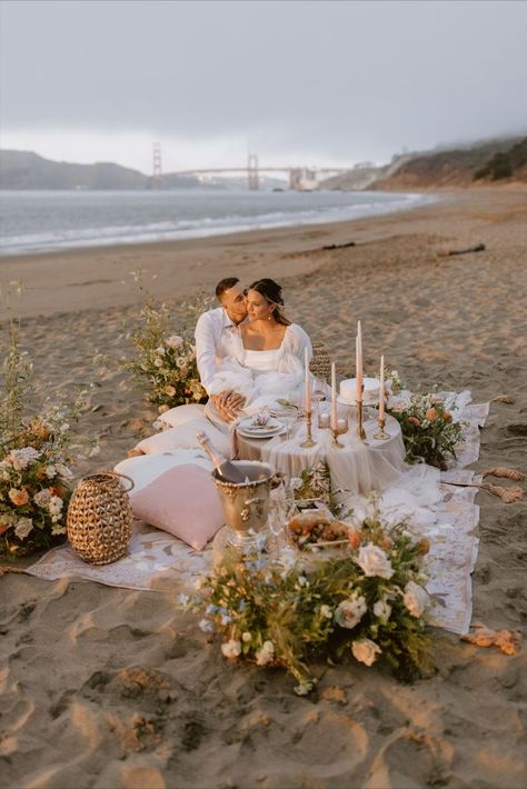 Bride and groom sitting at beach picnic with beautiful flowers and pink decorations at sunset Proposal Ideas Beach, Boho Beach Elopement, Wedding Proposal Ideas Engagement, Elopement Picnic, Romantic Beach Picnic, Cute Proposal Ideas, Proposal Pictures, Picnic Engagement, Beach Proposal