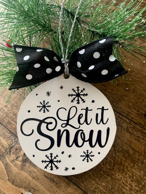 This Let it Snow ornament is painted in white and the black is done in vinyl. We complete each ornament with a hanging cord and bow. Comes ready to hang. The perfect gift to give or to keep for yourself. Dimensions 4" tall Let It Snow Ornaments, Cricut Joy Ornaments, Cricut Wooden Ornaments, Diy Vinyl Christmas Ornaments, Diy Black Christmas Ornaments, Wooden Rounds Christmas Ornaments, Painted Wood Christmas Ornaments Diy, Vinyl Christmas Ornaments Cricut, Christmas Cricut Ornaments