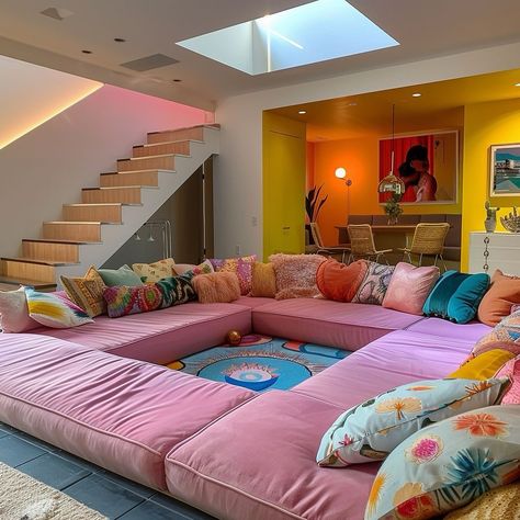 OUR NUMBER ONE POST ON PINTEREST! This vibrant, retro-inspired living space is a modern conversation pit reimagined for today’s lifestyle. The sunken pink sectional, adorned with an array of playful, patterned pillows, creates the perfect spot for lively discussions and intimate gatherings. Overhead, a skylight floods the area with natural light, enhancing the cheerful ambiance and making it an inviting haven for connection. Bold yellow and orange accents in the adjoining dining area, along w... Diy Conversation Pit, Modern Conversation Pit, Conversation Pit Living Room, Eclectic Interior Design Vintage, House Aesthetics, Funky Living Rooms, Conversation Pit, Princess Palace, Room Styling