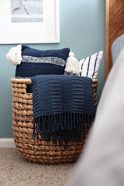 A wicker catch-all adds a rustic touch to a bedroom and creates an instant way to store pillows with ease. If you get one that's big enough, you can add throw blankets to the basket as well. Click through for more on this and other bedroom throw pillow storage ideas. Pillow Storage, Throw Pillows Bedroom, Teen Boy Bedroom, Spare Bedroom, Wicker Basket, Blue Bedroom, Guest Bedrooms, Organization Bedroom, Western Decor