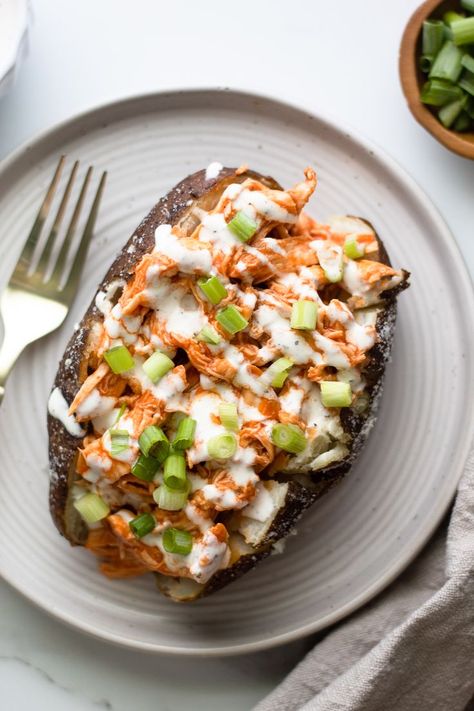 garnished buffalo chicken baked potato on a plate