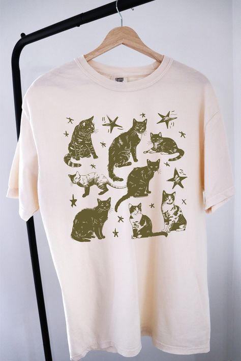 Vintage 90s Tattoo Cat Tshirt ⭐ Welcome to K & K Custom Tees! ⭐  - Indulge in pure comfort with our Comfort Colors Shirt. Soft, relaxed, and available in a variety of colors! ⭐SHIRT DETAILS⭐  -High Quality fabric  -100% ring-spun US cotton -Designed and printed in the USA  ⭐ PLEASE NOTE ⭐ -For an oversized look, we suggest to size up 1-2 sizes. These shirts run like standard unisex tees. Please see size chart for a more fitted look!  -Colors may vary based on your monitor or screen display! ⭐CARE INSTRUCTIONS ⭐ -Machine wash inside out in cold water  -Tumble dry medium or hang to dry  -Do not dry clean or iron directly onto the design  ⭐PROCESSING & SHIPPING TIMES ⭐ -Processing time: 3 to 5 business days  -Shipping time: US - 2 to 5 business days  ⭐OUR GOAL⭐  -Delivering top-notch t-shirts Cat Tshirt Design Ideas, Screen Print Tshirt Design, Tshirt Vinyl Ideas, Aesthetic T Shirts Vintage, Retro T Shirt Designs, Cool Shirt Designs Graphic Tees, Graphic Tees Style, Simple Graphic Tees, Tshirt Print Ideas