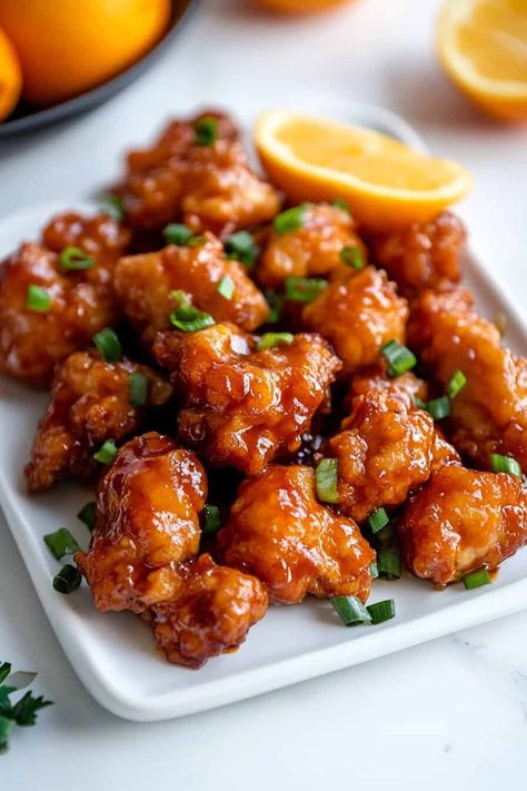 Slow Cooker Orange Chicken. A plate of crispy orange chicken bites, glazed with a sticky orange sauce, garnished with fresh scallions. A wedge of fresh orange sits in the background, adding a burst of color. Slow Cooker Orange Chicken Recipes, Orange Chicken Crockpot Recipes, Crockpot Orange Chicken Recipe Easy, Easy Orange Chicken Crock Pot, Orange Chicken Recipe Crockpot, Orange Chicken Instant Pot, Orange Chicken Crockpot, Asian Banquet, Crockpot Orange Chicken Recipe