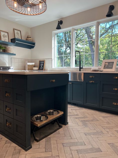 This kitchen is the ultimate inspiration for any dog lover out there! The center island has a built-in nook specifically designated for a dog food and water dish! It blends in seamlessly to the dark cabinetry and the herringbone floor adds so much character to this space!   New Construction | Home Trends 2024 | Home Design | Minnesota Home Trends Kitchen Dog Bowls Built Ins, Dog Bowl Kitchen Island, Dog Bowls In Island, Island With Dog Bowls Built Ins, Kitchen Island Dog Bowl, Dog Bowl Kitchen, Garage Shoe, Dog Feeding Station, Small Kitchen Island