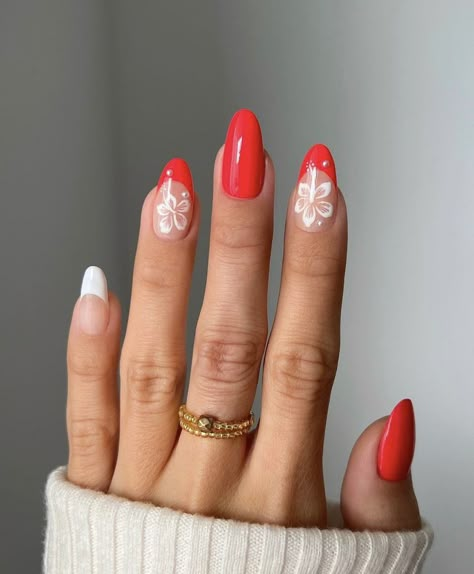 A girl with red French tip nails and two little white flower designs. Nails Summer Oval, Red Nails Acrylic Summer, Hawaiian Vacation Nails, Short Nails Hibiscus Flower, Red Tropical Nails, Red Flower French Tip Nails, Almond Nails With Hibiscus Flower, Hibiscus Flower Nails Red French Tip, Oval Summer Nails