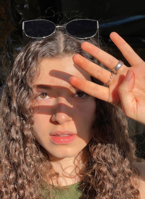 A girl with the sun light on her face. Wearing sunglasses a green shirt and two rings. Curly hair and brown eyes. Sunlight Pictures Photo Ideas, Selfie Poses In Sunlight, Sunlight Pictures Selfie, Sunny Lighting Reference, Sun Selfie Ideas, Sunlight Selfie Ideas, Sunlight Poses, Sunlight Reference, Sunlight On Face