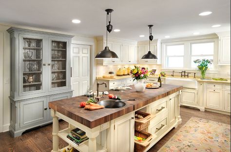 Butcher's block island in kitchen with cream-colored cabinets and hand-scraped hardwood floors. Kitchens With Butcher Block Countertops, Kitchen Island With Cooktop, Farmhouse Kitchen Light Fixtures, Dapur Rustic, Kitchen 2021, Kitchen Island With Sink, Farmhouse Kitchen Lighting, Butcher Block Kitchen, Farmhouse Kitchen Island