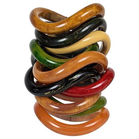 Collection of End of Day Bakelite Squiggle Bracelets from the 1960's likely made of bakelite from an earlier period. Each is shaped like a potato chip and stack perfectly on top of each other. Wonderful colorations which work beautifully in a variety of different configurations. Complete wardrobe includes black, marbleized greens, deep peach, red and banana tones. 11 pieces total. 1960's USA. .5" width. Openings oval in form, 2 3/8" x 2". 1970s Accessories Jewelry, Red Objects, Nigerian Jewelry, Coconut Bowls, Dope Jewelry Accessories, 1960s Jewelry, Bakelite Jewelry, Potato Chip, A Potato