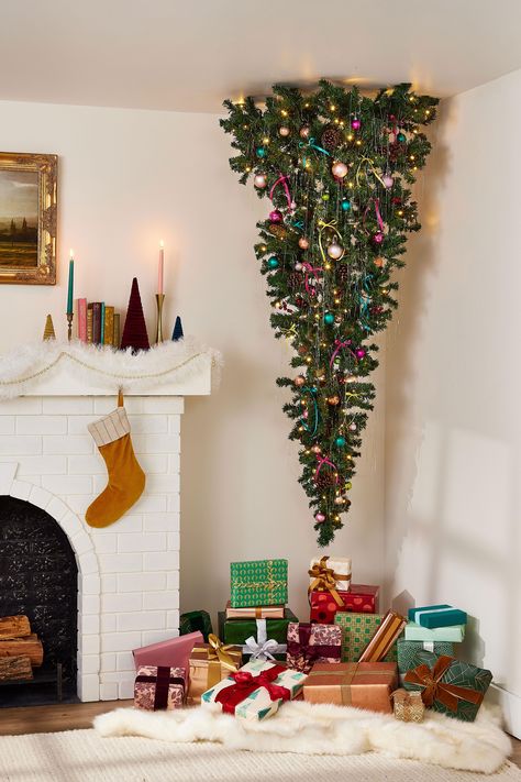 Surprise Santa with a playful upside-down Christmas tree that hangs from the ceiling—and leaves ample room for gifts below. Learn how to hang and decorate one in your home. How To Hang A Christmas Tree Upside Down, Tree On Wall Christmas, Upcycle Fake Christmas Tree, Upside Down Christmas Tree Hanging, Christmas Tree Upside Down, Upside Down Tree Christmas, Diy Upside Down Christmas Tree, Christmas Tree On A Wall, Christmas Hanging Decorations Ceilings