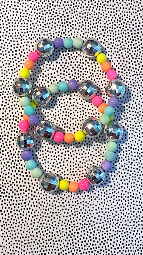 Bright rainbow acrylic beaded bracelet with disco ball accents. *The number of beads between the disco balls may vary based on your wrist size. The bracelet pictured is 7 inches. This listing is for one handmade beaded bracelet. Please measure your wrist in inches before ordering to ensure that you order the correct size. - Measure with a string or measuring tape around your wrist where you comfortably like your bracelets to sit. This bracelet is made with strong and stretchy elastic chord. To a Disco Beads Bracelets, 80s First Birthday Party, Disco Ball Bracelet, Disco Ball Jewelry, Rainbow Disco Birthday Party, Disco Crafts For Kids, Girls Disco Birthday Party, Kids Disco Party Ideas, Disco Kids Party