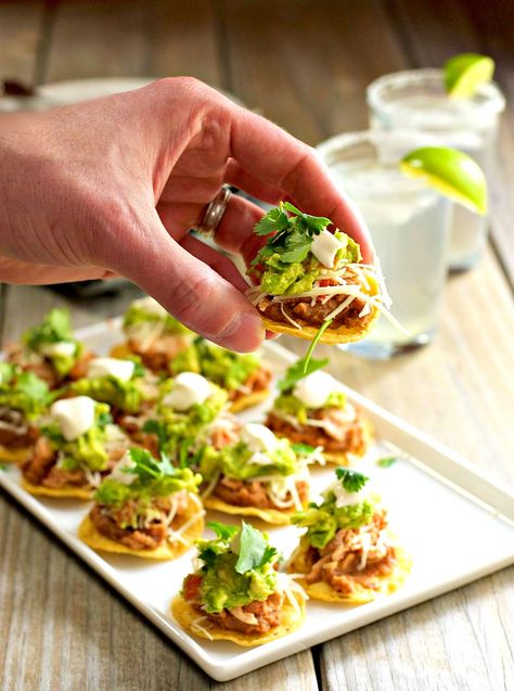 Chicken tostadas are a festive and delicious party food especially when they're bite size! Five layers of flavor piled on to a round tortilla chip (instead of traditional tostada shells). This version has refried beans, tender chicken with Mexican spices, cheese, guacamole, sour cream and fresh cilantro. But it's entirely versatile, swap in any ingredients you like! Mexican Appetizer Recipes, Mexican Finger Foods, Mexican Refried Beans, Mexican Appetizer, Mexican Dinner Party, Mexican Party Food, Chicken Tostadas, Mexican Appetizers, Frijoles Refritos