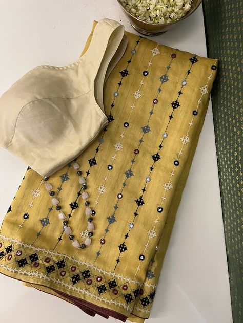 A handwoven mustard saree with with black beige and grey combination of kutch work all over the saree. The border and body of the saree has mirror work like detailing . The saree comes with a self blouse piece with work on sleeves Kutch Work Dress Designs, Work Wear Saree, Hand Embroidery On Saree, New Dress Design Indian, Kutch Work Saree, Mustard Saree, Mirror Work Saree Blouse, Mirror Work Border, Work On Sleeves