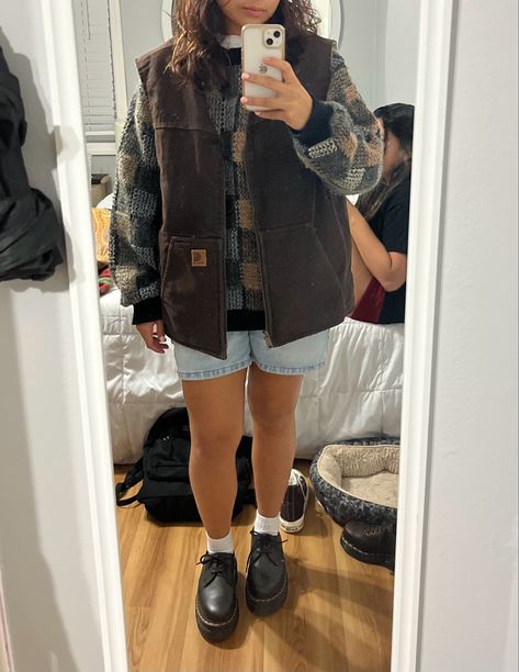 mirror picture. brown carhartt best. grandpa sweater. doc martnes. jorts How To Style A Sweater Vest Fall, Carhart Vest Girl Outfit, Outfits With Carhartt Vest, Carhartt Women Outfits Fall, Carhartt Gilet Outfit, How To Style Brown Doc Martens, Light Brown Vest Outfit, Women’s Carhartt Vest Outfit, Brown Sherpa Vest Outfit