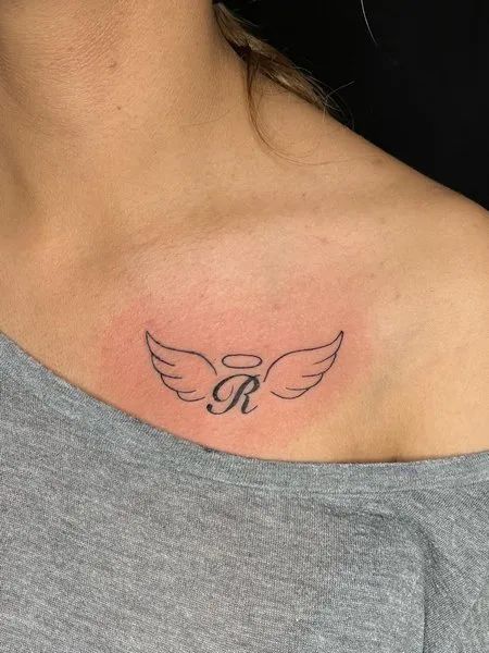 Angel Wings Chest Tattoo Small Angel Wings Tattoos, Initial Wings Tattoo, Angel Tattoo Wrist, Loved One Passing Tattoo, Wing Tattoos For Women, Angel Wings Initial Tattoo, Mini Tattoos Angel Wings, Tattoos For Lost Ones, Angel Wings Chest Tattoo