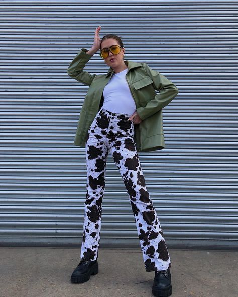 Girl posing in front of a shutter wearing cow print trousers and a green leather jacket Cow Print Pants Outfit, Cow Print Pants, Printed Pants Outfits, Green Leather Jackets, Western Babies, Printed Trousers, Flare Trousers, Printed Pants, Green Leather