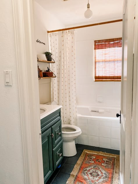 Our mini bathroom makeover gave us the neutral boho bathroom of our dreams (or at least one that'll hold us over until a remodel). With a painted moody green vanity, painted tile, beige beadboard and wood ac cents, this neutral boho bathroom was a game-changer in our little home. #neutralbohobathroom #bohobathroomdecor #neutralbathroomdecor #turkishrugbathroom #juterugbathroom #beadboardbathroom #greenbathroomvanity #openshelvesbathroom #bohobathroomideas Paint Bathroom Tile, Painting Bathroom Tiles, Paint Bathroom, Budget Bathroom Remodel, Small Bathroom Ideas On A Budget, Casa Vintage, Boho Bathroom, Upstairs Bathrooms, Small Bathroom Ideas