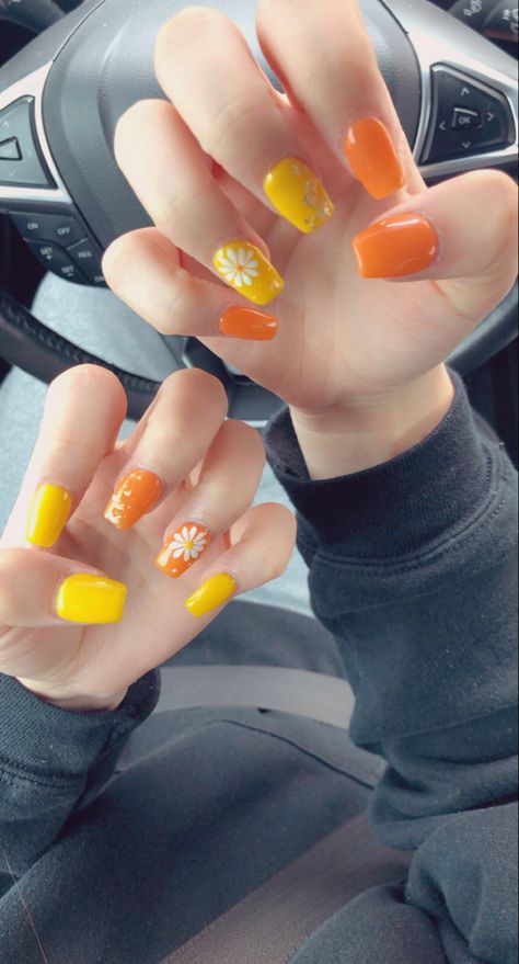 opposite designs and colors on each hand. cute flower and some gold foil used on acrylics. Yellow Orange Nails Acrylic, Yellow Nail Paint, Yellow And Orange Nails Summer, Orange Yellow Nails Summer, Yellow Orange Nails Design, Pretty Orange Nails, Yellow And Orange Nails Design, Nails Summer Yellow, Orange And Yellow Nail Designs