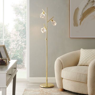 This 3-light floor lamp provides a mixture of modern and glam styles to elevate your living room arrangement. Crafted from steel with a shiny gold finish, it features a circular base and a tree-style silhouette with branches that angle out toward three corresponding fixtures. Each one holds an included LED bulb and is surrounded by a clear, multifaceted crystal glass shade. Measuring 5.5' tall and just under a foot wide, this lamp's small footprint makes it ideal for space-conscious rooms. Highl Room Arrangement, Light Tree, Crystal Floor, Crystal Floor Lamp, Ornament Stand, Tree Floor Lamp, Living Room Arrangements, Led Tree, Gold Floor Lamp