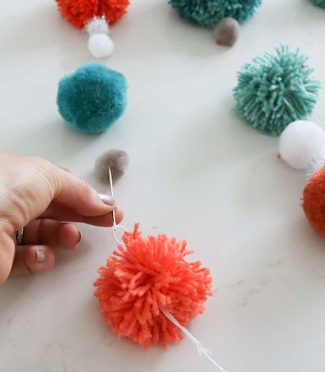 Looking to add a fun pop of handmade color to your home? May I suggest a DIY pom pom wall hanging?    Once you get started it’s easy to knock out a few of these guys, promise.  Gather your supplies:    Dowel rods  Thick string  Needle  Yarn in varying colors   Pom pom tool  (I used a large and small one)  Sharp scissors  Mini store bought pom poms (if you wish)    If you’re not the pom pom making type—good news—you can buy pre-made poms at most craft stores.    While I… Pop Pom Crafts, Diy Pompoms, Pom Pom Wall Hanging, Pompom Art, Pom Pom Wall, Artsy Decor, Pom Crafts, Sharp Scissors, Elderly Activities