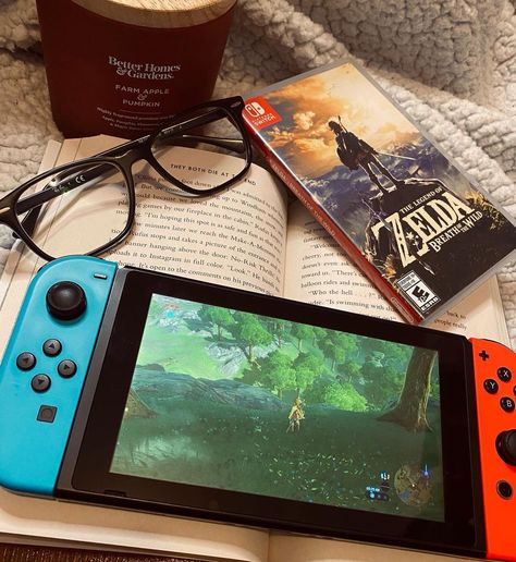 Nintendo Switch cozy gaming flatlay featuring Legend of Zelda : Breath of The Wild (BOTW). Also included: The book They Both Die at The End by Adam Silvera, Raybans black glasses, red Better Homes and Gardens Farm Apple and Pumpkin Candle, and fleece blanket Gamer Astethic, Zelda Game, Botw Aesthetic, Video Games Aesthetic, Gaming Aesthetic, Zelda Aesthetic, Nintendo Switch Zelda, Friendship And Dating, Discovery Call