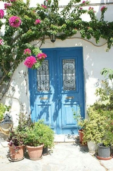 Blue greek style front door with pink climber and pots Spanish Style Front Door, Beach House Front Door, Blue Painted Door, Greek Style Home, Mediterranean Doors, Mexico House Ideas, Modern Entrance Door, Greek Decor, Blue Front Door