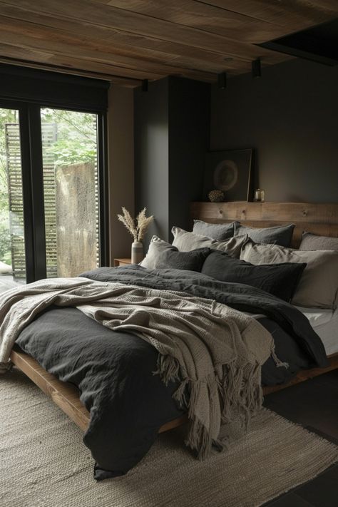 Modern bedroom with a wooden bed, gray and beige bedding, a throw blanket, and large windows revealing a leafy outdoor view. Dark And Moody Bedroom, Moody Bedroom Ideas, Modern Rustic Bedrooms, Neutral Bedrooms, Moody Bedroom, Dark Bedroom, Dark Home Decor, Dekorasi Kamar Tidur, Dark Home