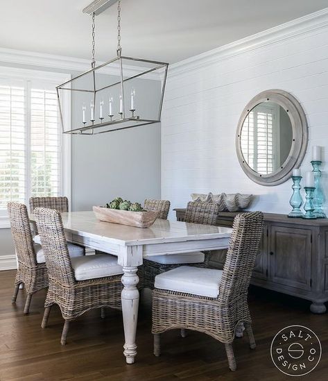 A Darlana Linear Chandelier hangs over a whitewashed dining table surrounded by wicker dining chairs placed in front of a dark stained wood buffet cabinet. Cottage Dining Rooms, Wicker Dining Chairs, Coastal Living Rooms, Beach Cottage Decor, Coastal Living Room, Beach Cottage Style, Nautical Home, Wooden Wall Art, Beach Cottages