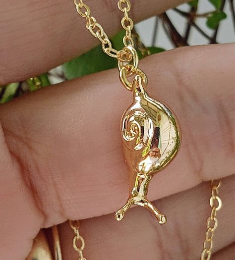 Tiny Gold Snail dangling from a delicate 18 inch 18k gold plated chain. Absolute perperfection. This sweet little snail is truly special and one of my very favorite designs. Exquisite in detail, with a rich gold finish and fine quality make this Snail Necklace is an ideal gift for the garden enthusiast and nature lover on your list. An equally lovely pair of Gold Snail Earrings are also available from A Cheerful Nest.  Your gorgeous Gold Snail Pendant will arrive in an organza pouch with a match Whimsical Gold Pendant Charm Necklace, Snail Jewellery, Snail Shell Earrings, Snail Accessory, Snail Necklace, Snail Wire Wrap, Body Jewelry Piercing, Themed Jewelry, Gold Plated Chains