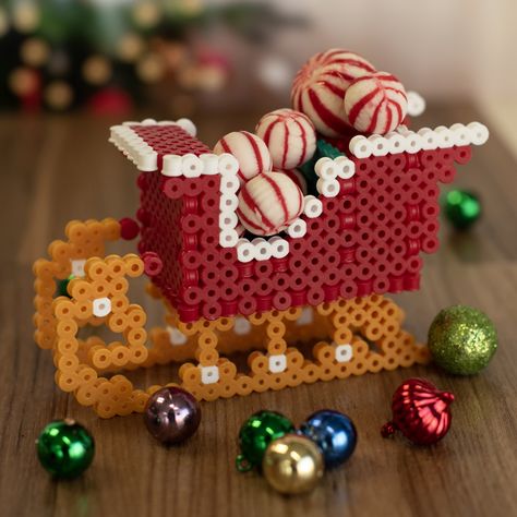 This festive three-dimensional sleigh created with Perler fuse beads can be used to hold holiday treats or made into a tree ornament by adding your own hanger. Perler Bead Ornaments Pattern, Decor Beads, Christmas Perler Beads, Easter Egg Ornaments, 3d Perler Bead, Santa's Sleigh, Perler Ideas, Leaf Cards, Craft Fair Ideas