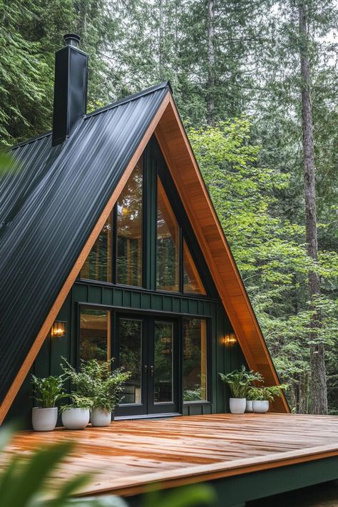 View from the deck of a deep dark green a frame cabin with full glass windows and natural wood door with glass panels chromed chimney on the roof. Check out all of these stunning and chic dark A-frame houses that pack a ton of charm into a small forest retreat. White Cabin Interiors, A Frame Entrance, A Frame Accent Wall, Glass Cottage House, Rustic A Frame Cabin Interior, Small A Frame Interior Design, Tiny A Frame House Plans, A Frame Cabin Exterior Colors, A Frame Cabin Lighting